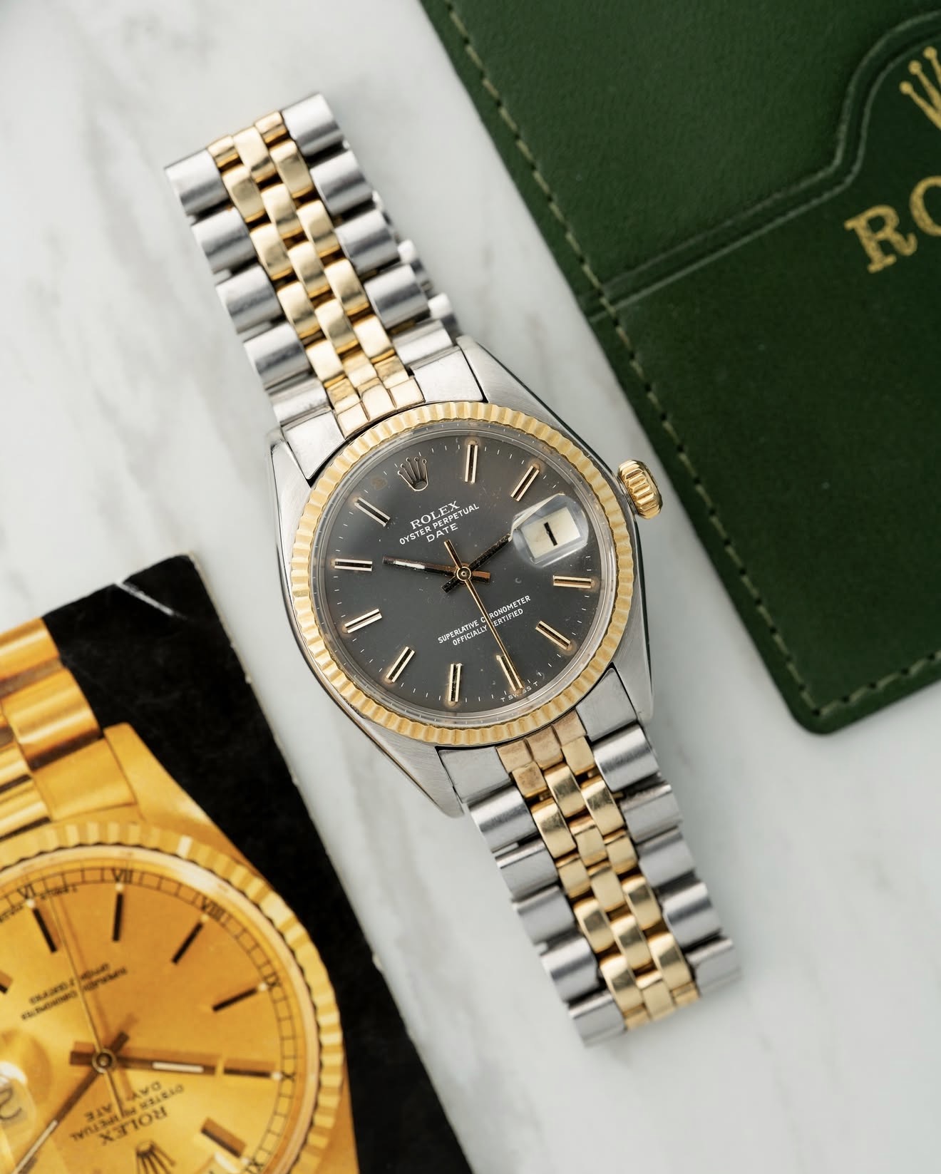 Two-tone Rolex Oyster Perpetual Date with grey dial beside green Rolex pouch